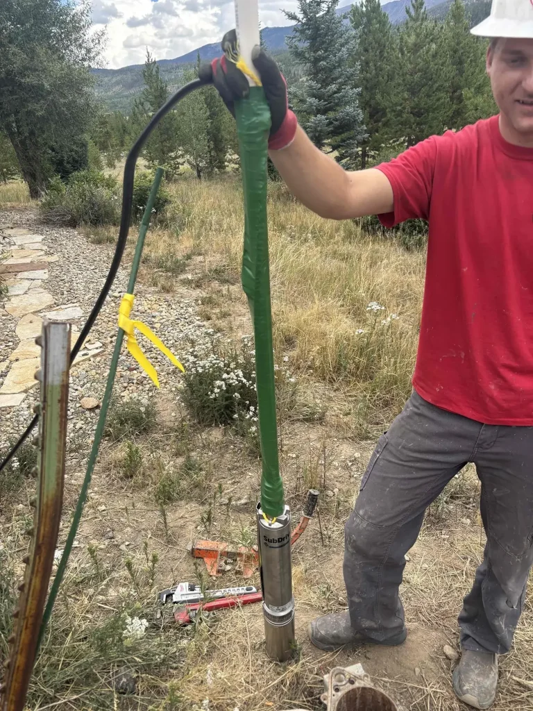 Technician with a new submersible well pump at the wellhead in Fraser, Colorado