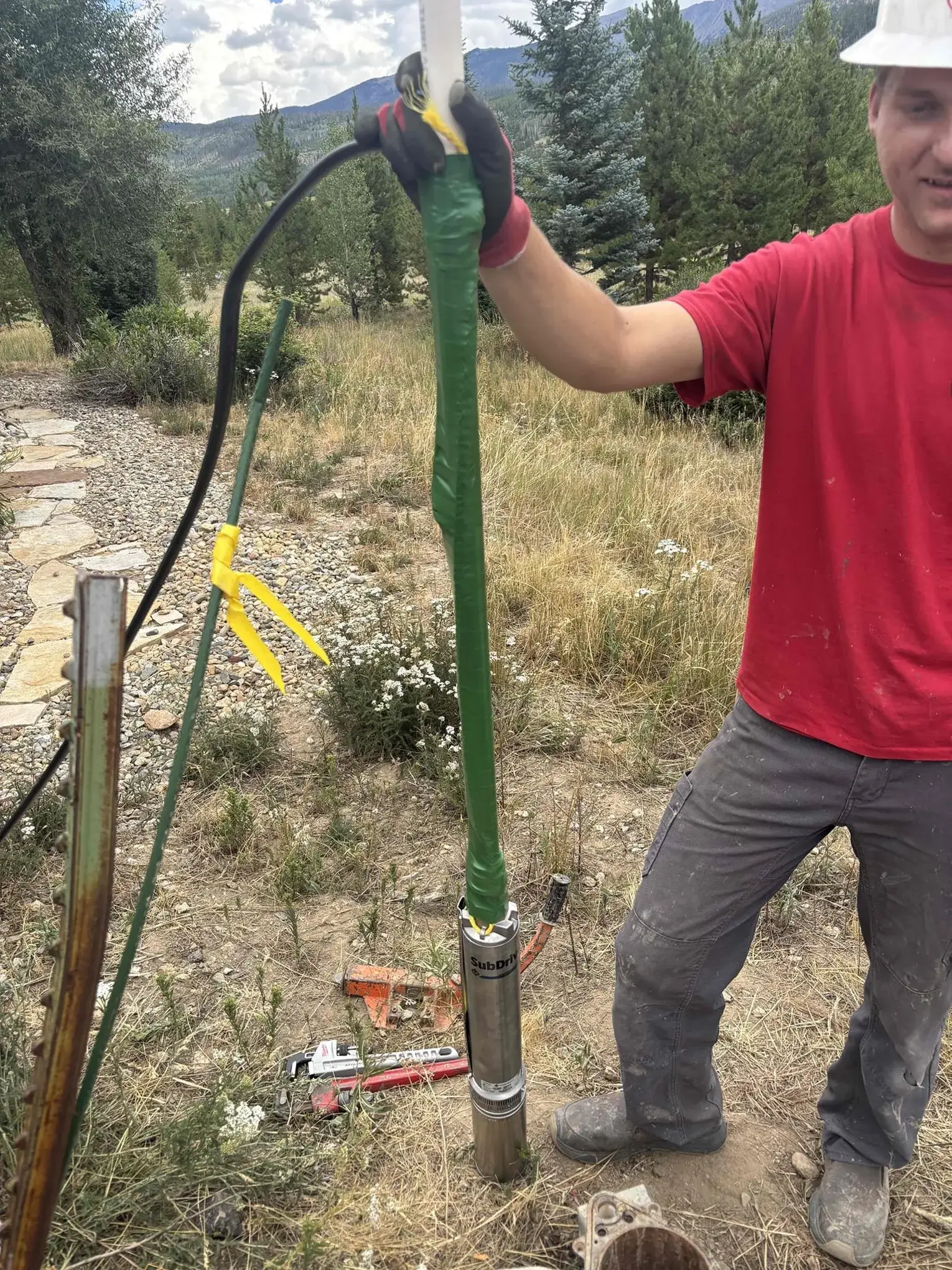 Technician with a new submersible well pump at the wellhead in Fraser, Colorado